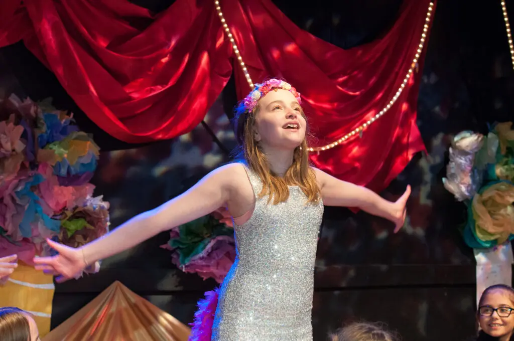 a girl in a dress with her arms out