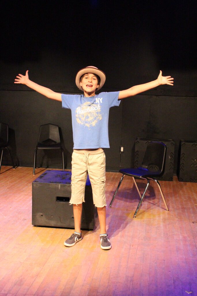 a boy standing on a stage with his arms outstretched