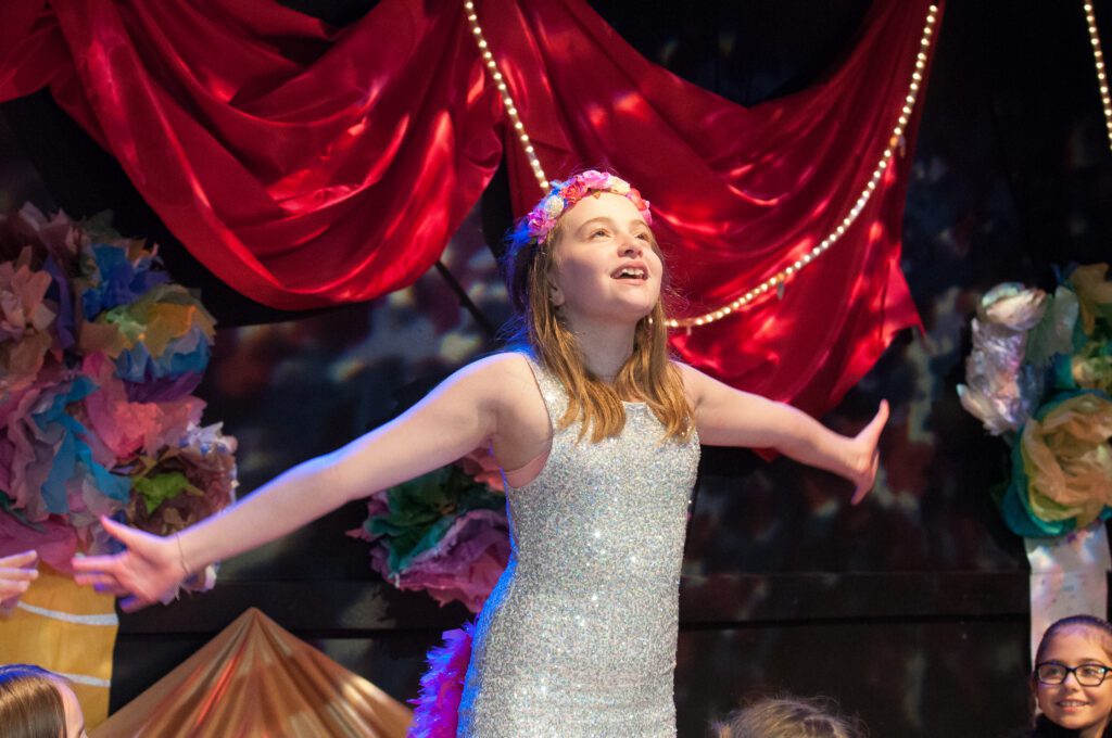 a girl in a dress with her arms out