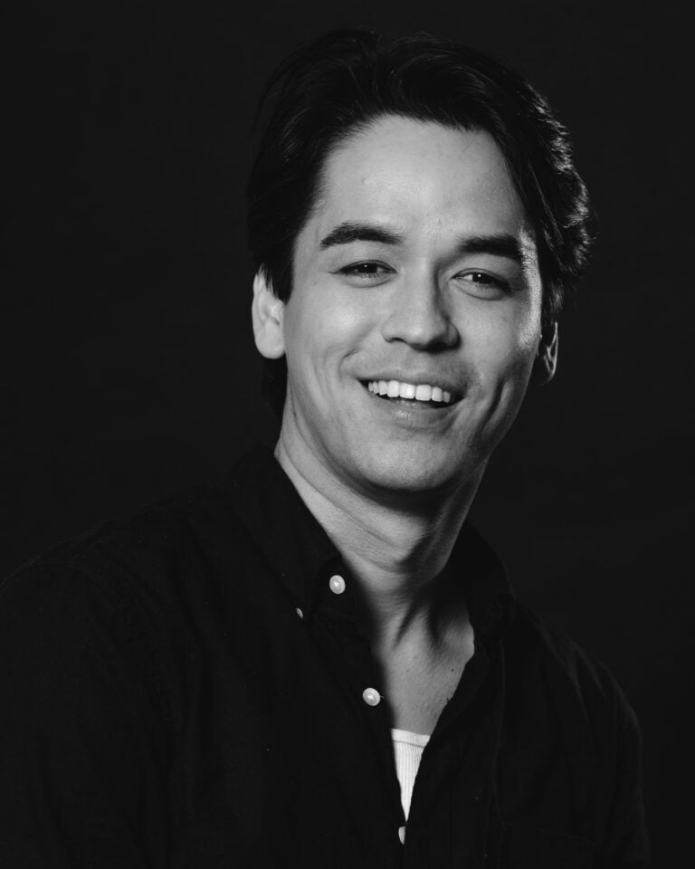 Headshot of Sky Smith smiling with a dark shirt against a black background.