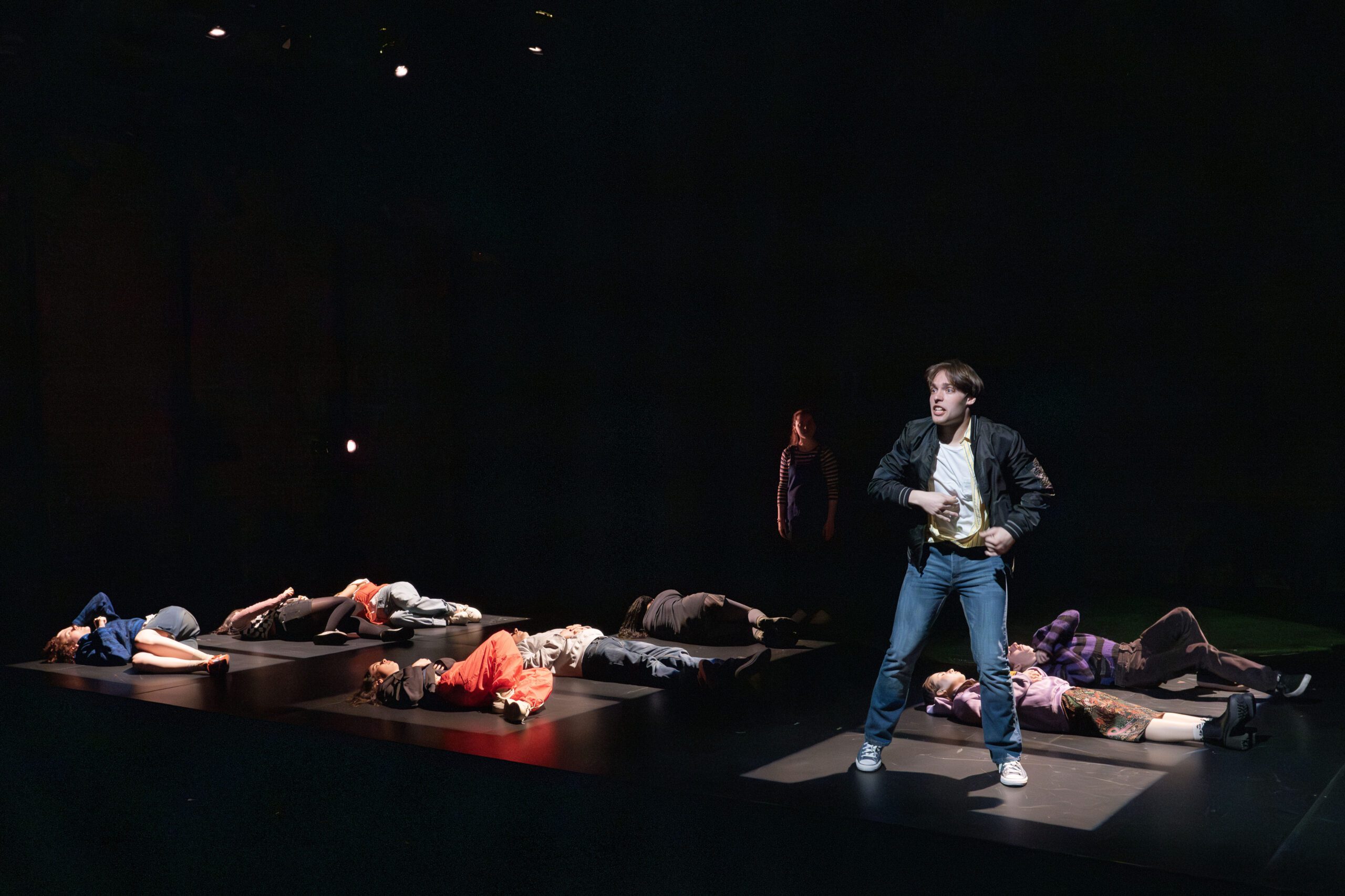 a man standing on a stage with people lying on the ground