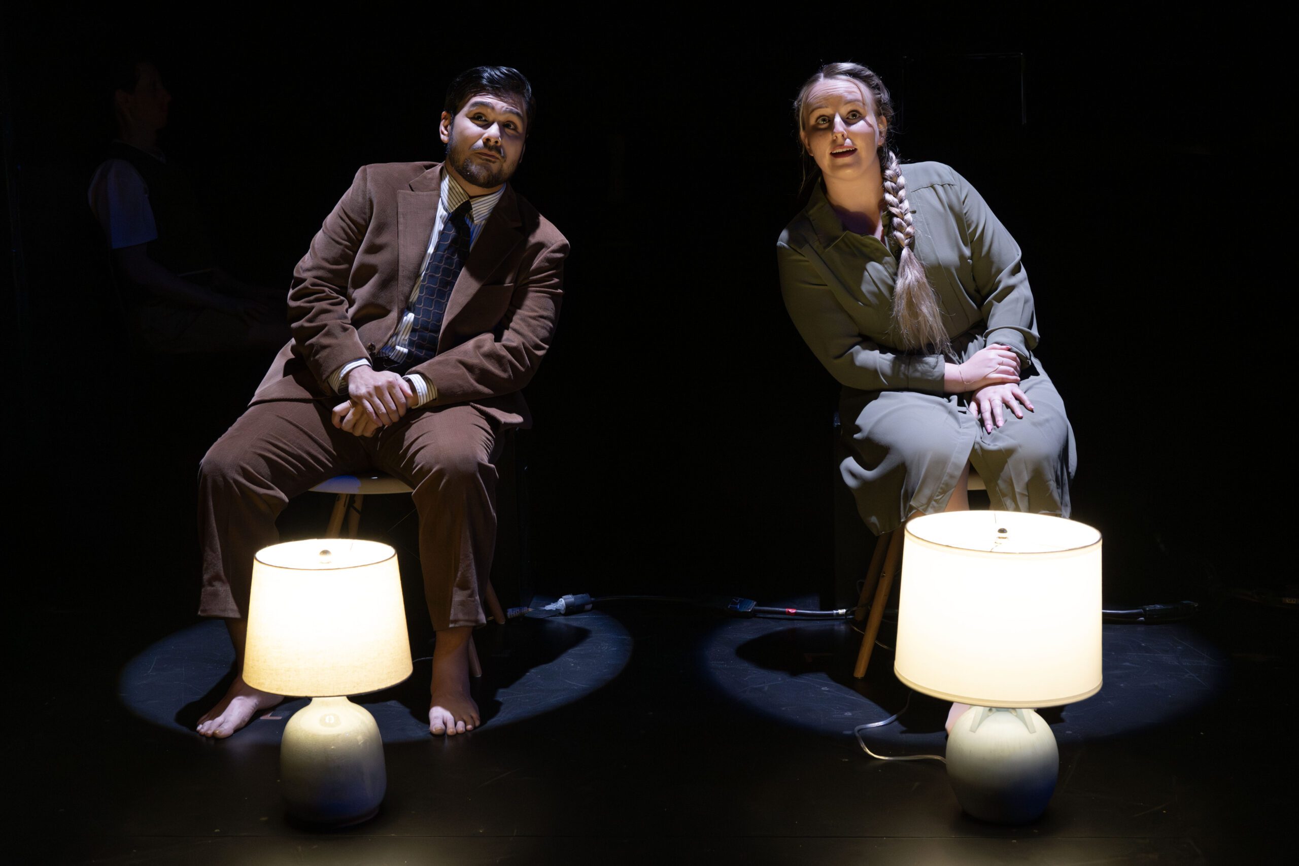 a man and woman sitting on stools with lamps on a stage