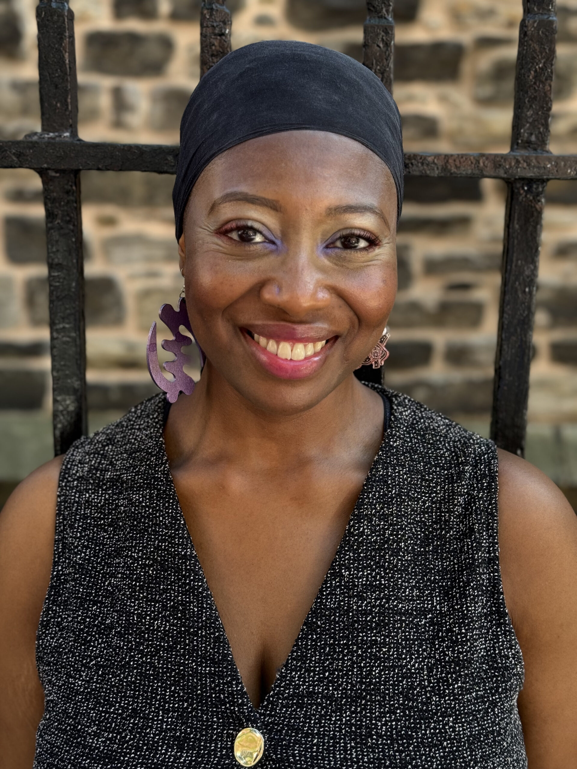 Smiling Black woman in a headwrap and statement earrings