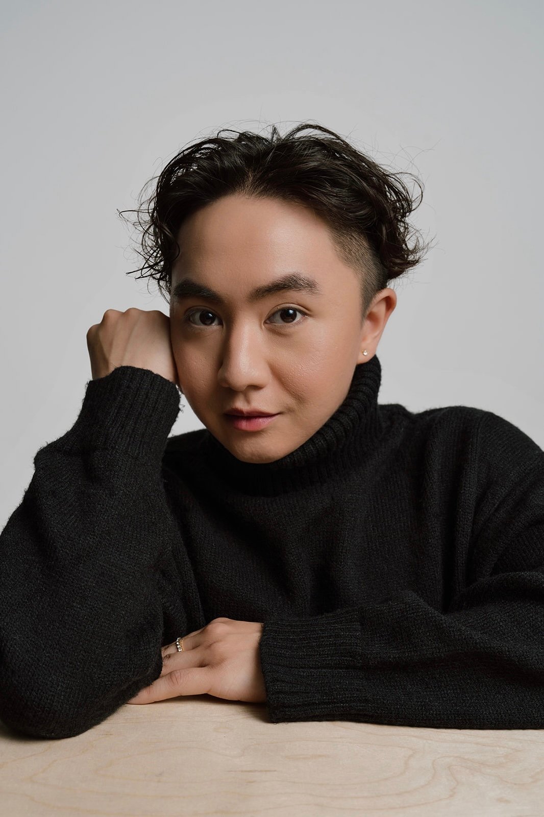 Portrait of a person with dark hair wearing a black turtleneck sweater.