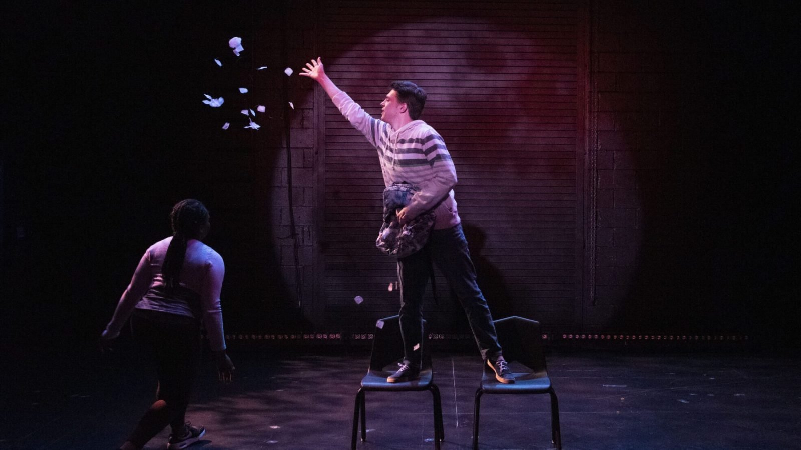 a man standing on a chair with a woman in the background