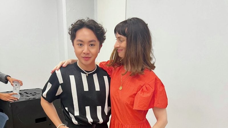 Two people posing indoors, one in red dress, one in black and white top.