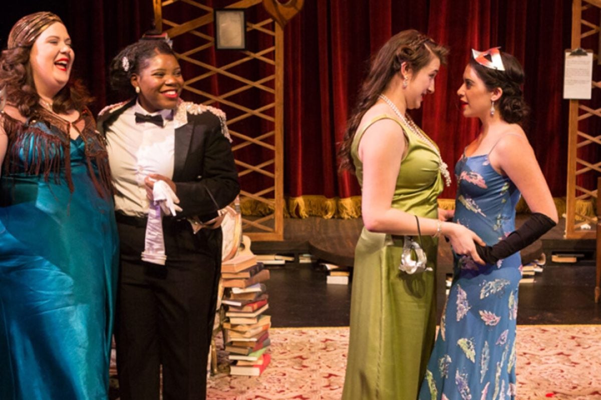 Four actors in costume performing in a theatrical production.