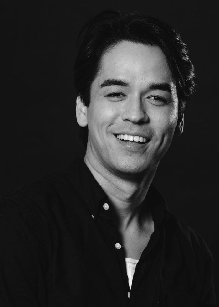 Headshot of Sky Smith smiling with a dark shirt against a black background.