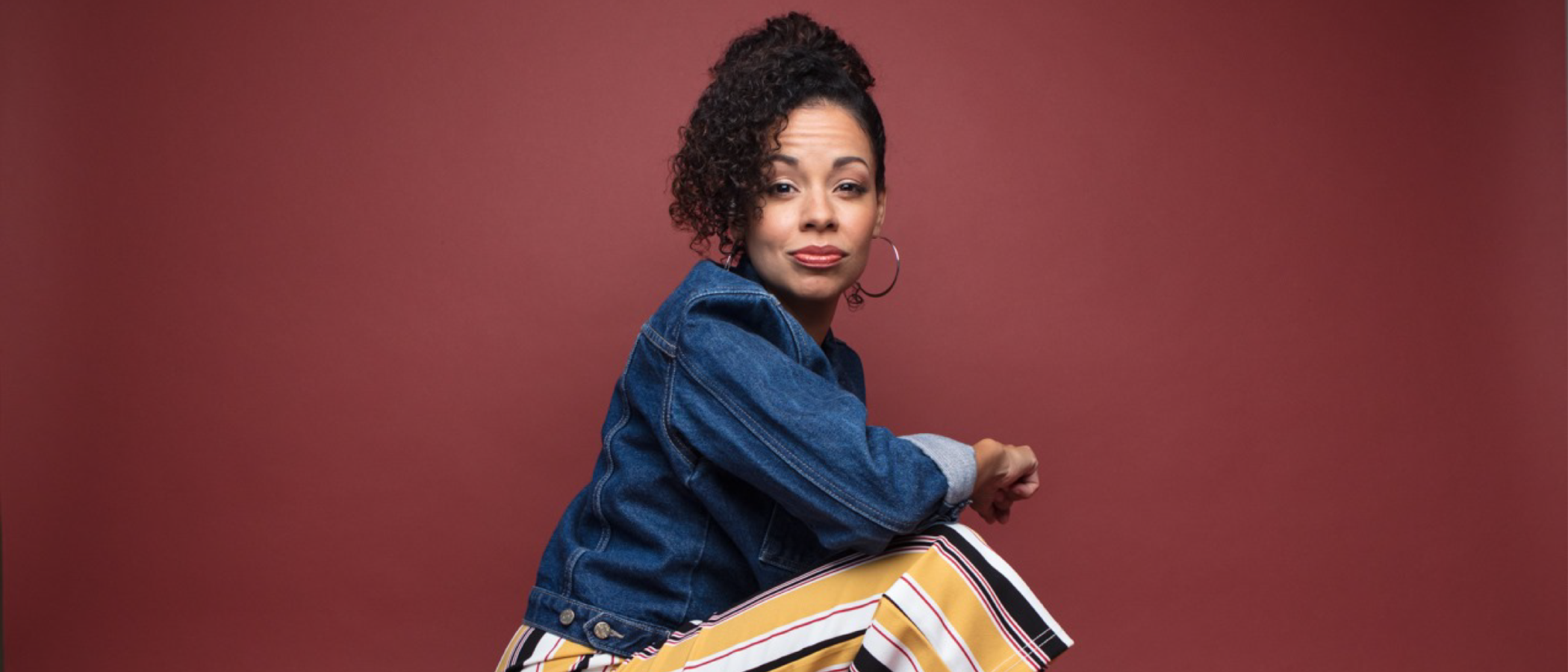 Latina actress in denim jacket and striped pants, embodying the journey back to the stage.